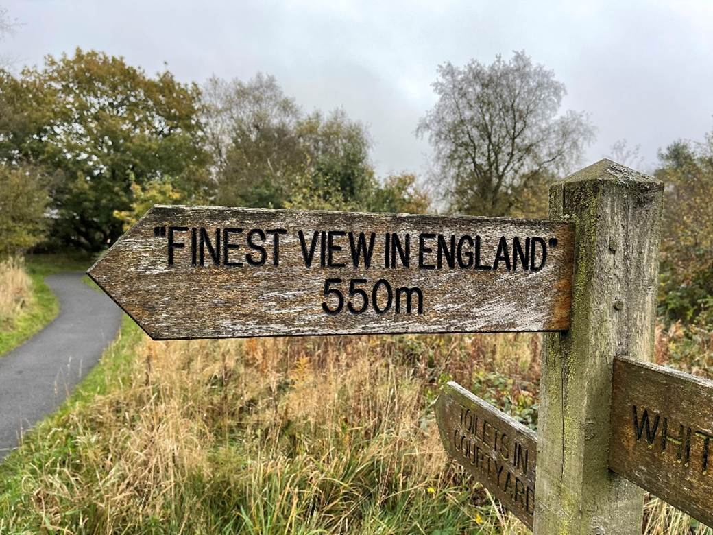 A sign post with a road and trees

Description automatically generated